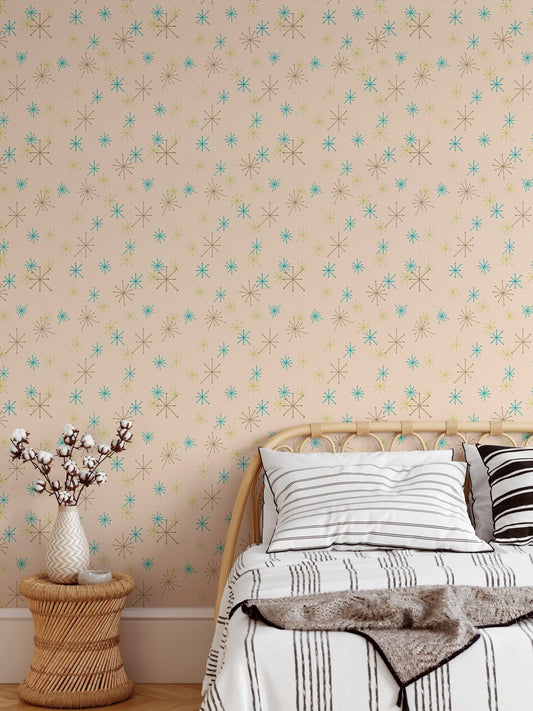 Colorful snow fleck wall mural behind a wooden bed with white and grey striped pillows.