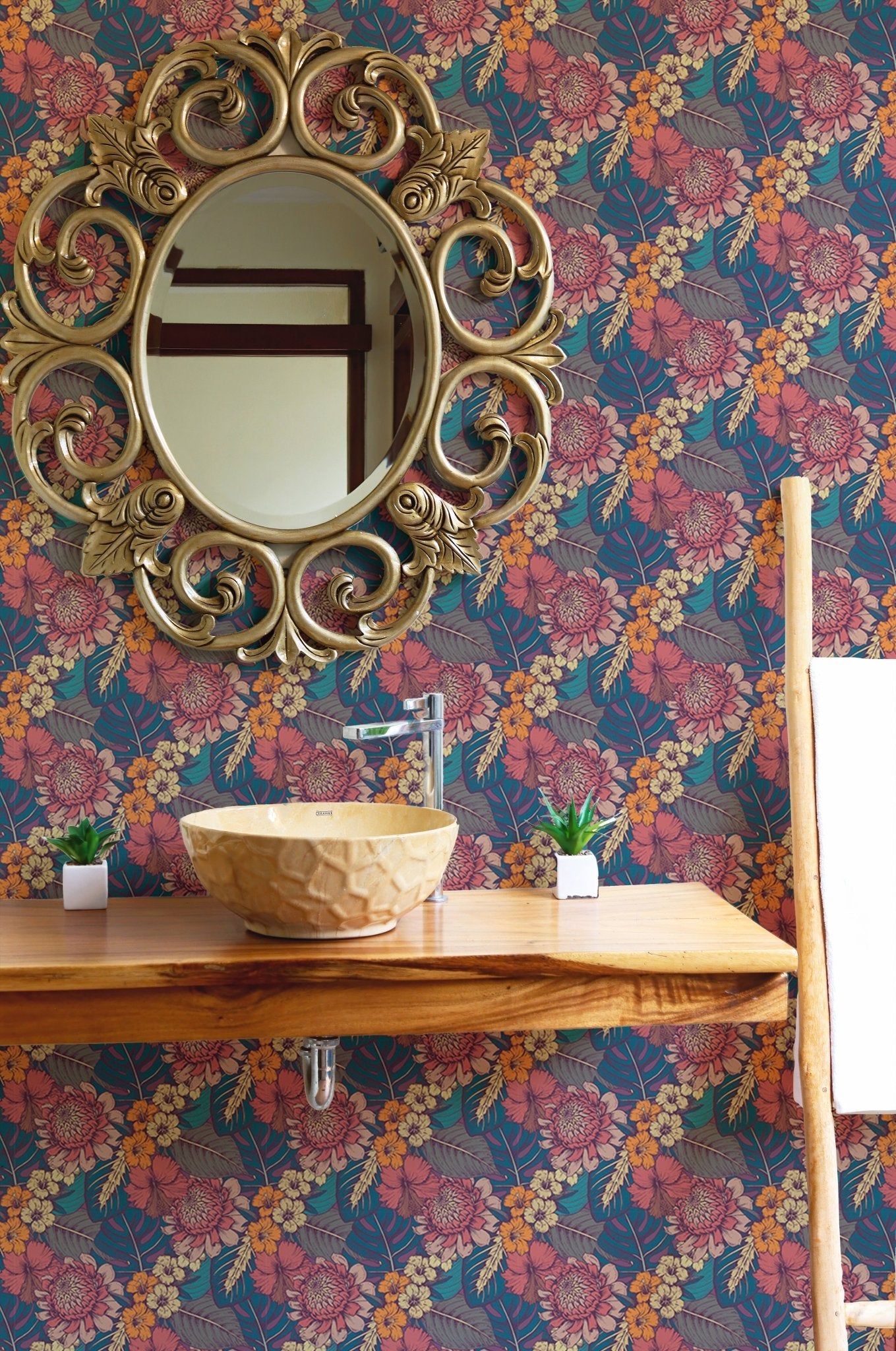 Flower wallpaper in a washroom area with a gold circular mirror and wooden counter.