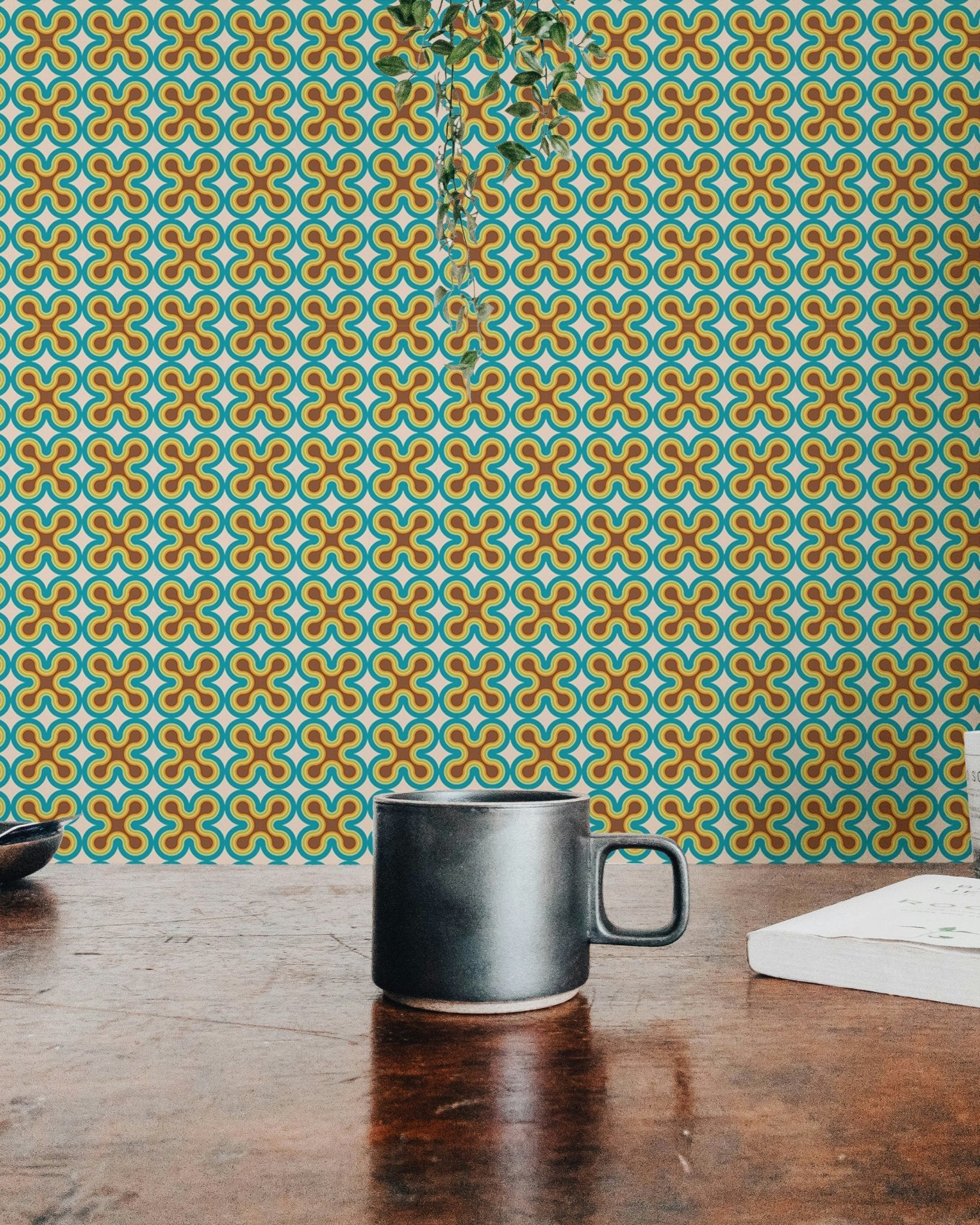 Intricate art pattern wall mural seen behind a dark mug on a wooden desk.