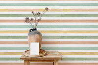 Pale green and peach striped wallpaper behind a wooden stool and ceramic vase