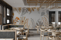 Dining area wall mural with grey and ochre watercolor leaf patterns.
