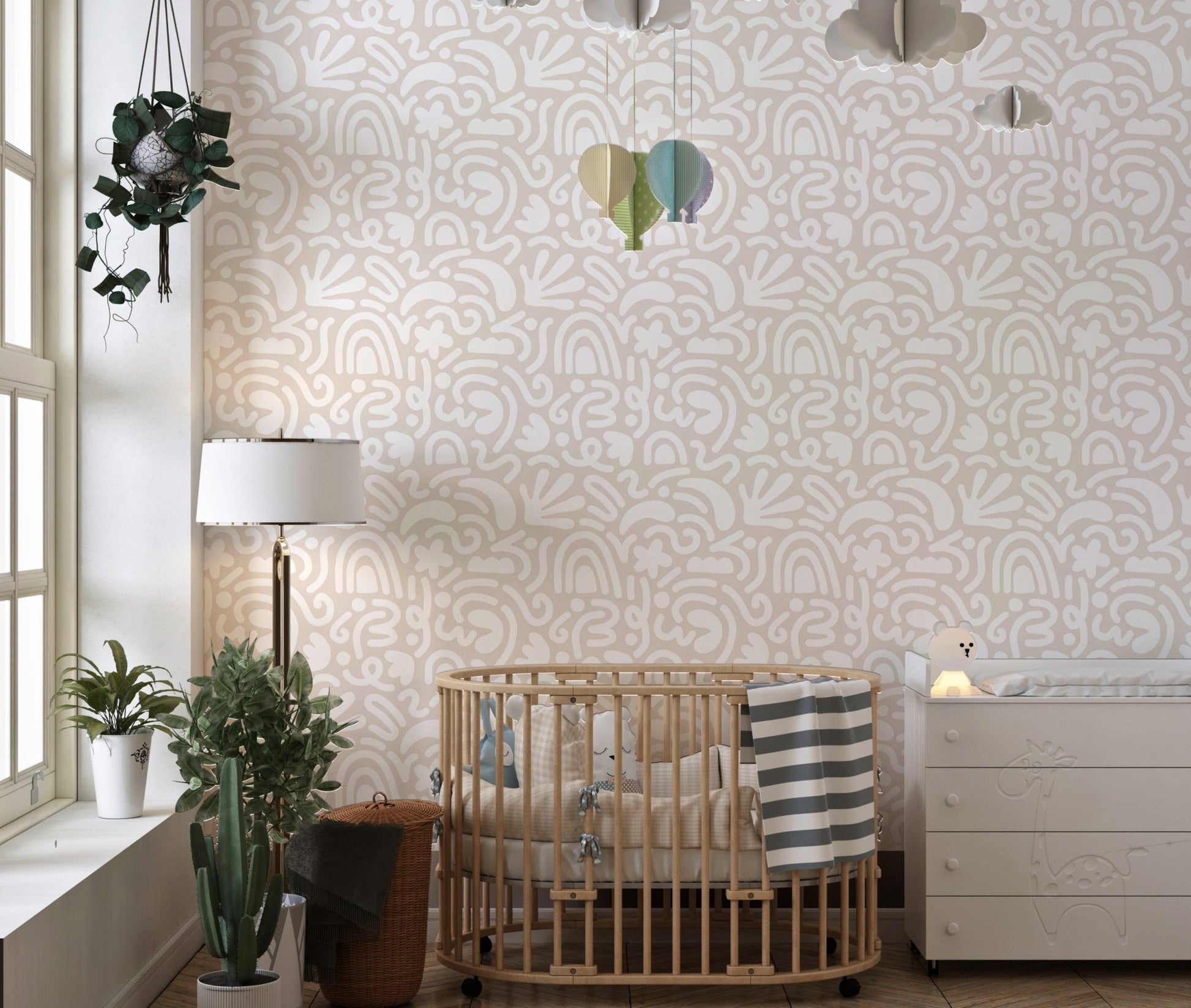 Abstract art wallpaper in a nursery with a wooden cot and hanging toys.