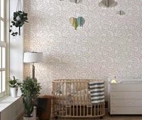 Abstract art wallpaper in a nursery with a wooden cot and hanging toys.