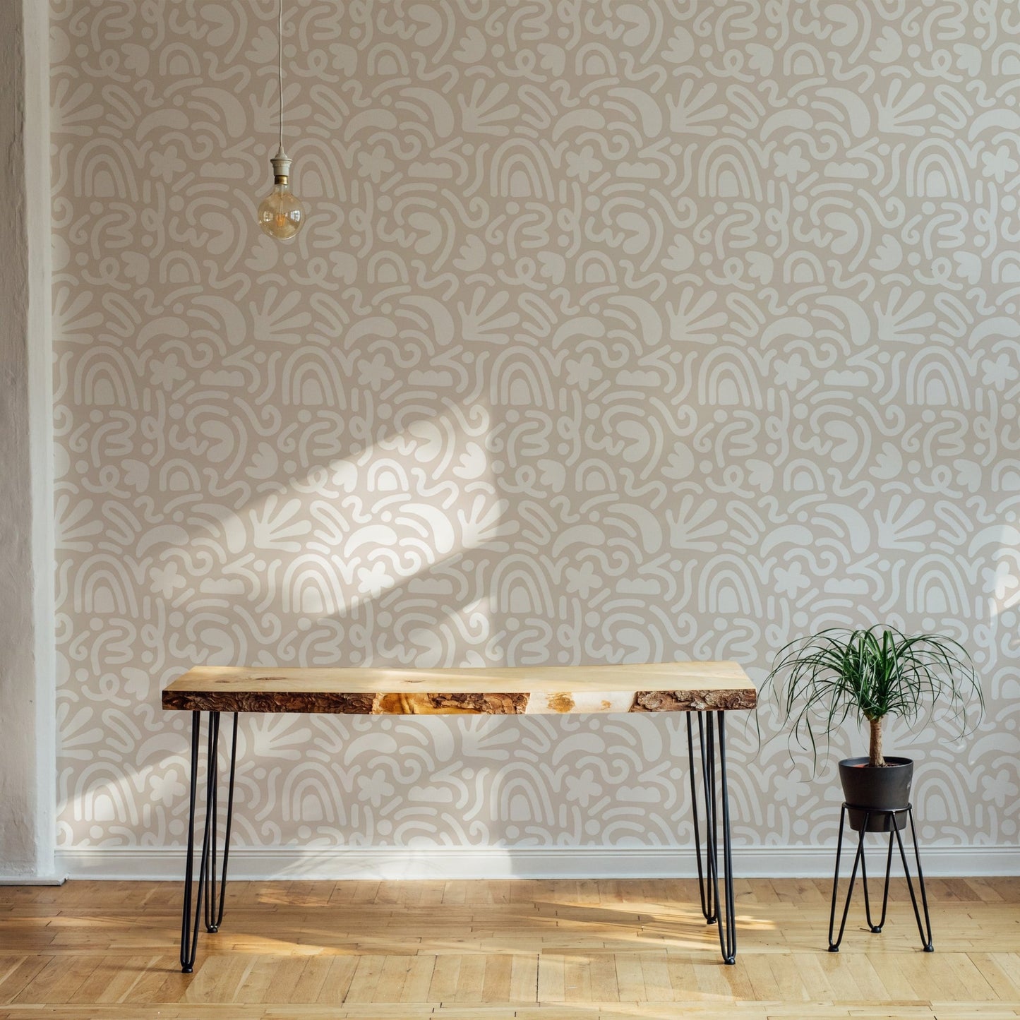 Minimalist abstract wallpaper behind a wooden desk and indoor plant.