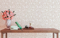 Light beige scandinavian wallpaper behind a wooden table with pink flowers.