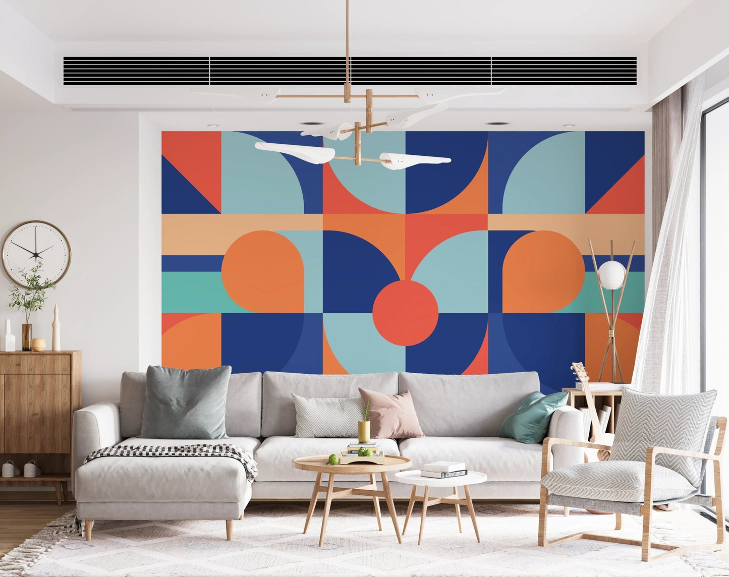 Modern geometric wall mural behind a grey sectional sofa in a bright room
