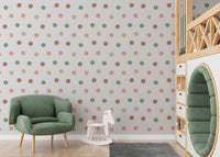 Kids play area with a green armchair and earthy tone polka dot wallpaper.
