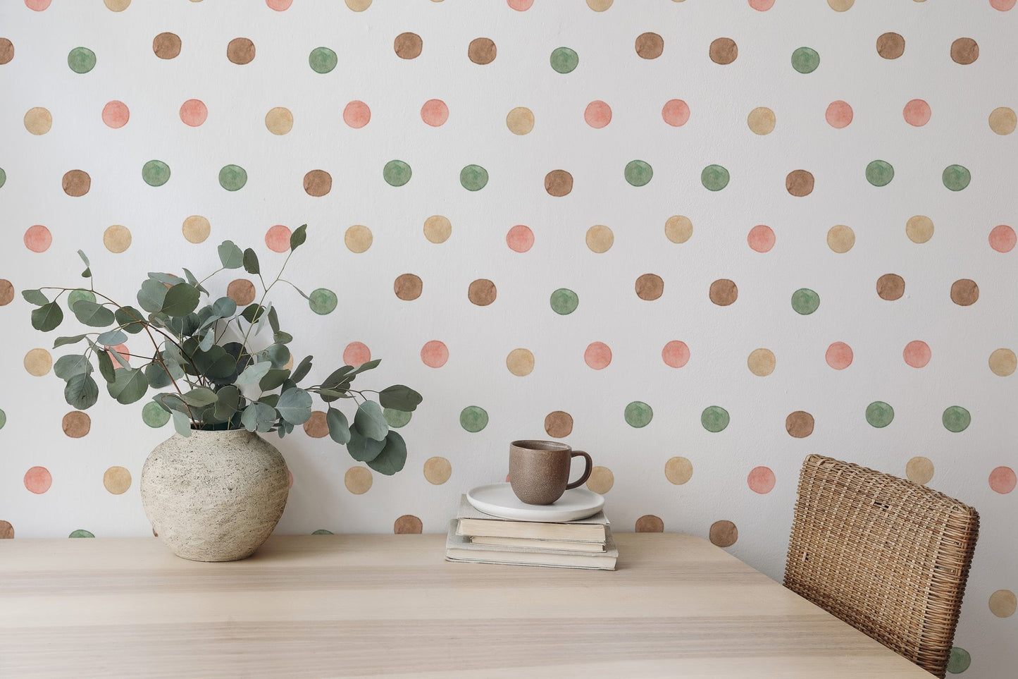 Green and terracotta dot wallpaper behind a wooden desk with a white vase.