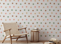 Woven chair next to a wall with earthy watercolor dot wallpaper.