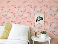 Pink marine life wallpaper in bedroom behind a white bed with a yellow cushion.