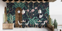 Dark background wall mural with teal foliage in a restaurant with white chairs.