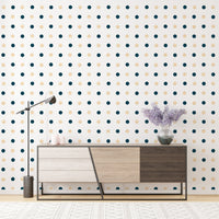 Minimalist polka dot wallpaper behind a wooden sideboard and purple flowers.