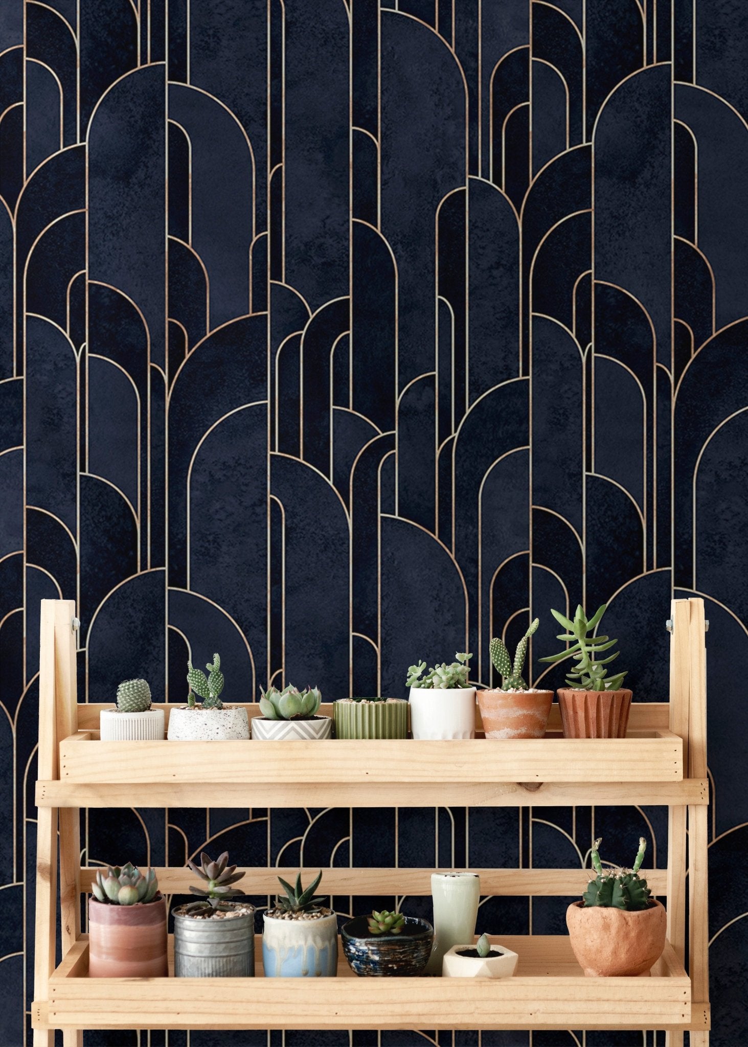 Patterned deco wallpaper behind a wooden plant stand with small succulents.