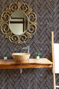 Bathroom vanity area with dark brown brick repeat pattern wallpaper and gold mirror.