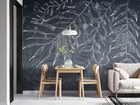 Leafy shadow wall mural in a minimalist dining area with light wood furniture.