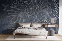 Large wall mural with leaves patterns behind a dining table and chairs.