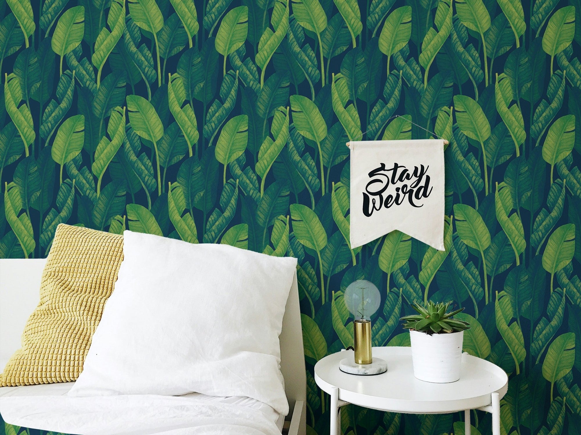 Bedroom wall with Dark Green Color Banana Leaves Wallpaper and white bedding.