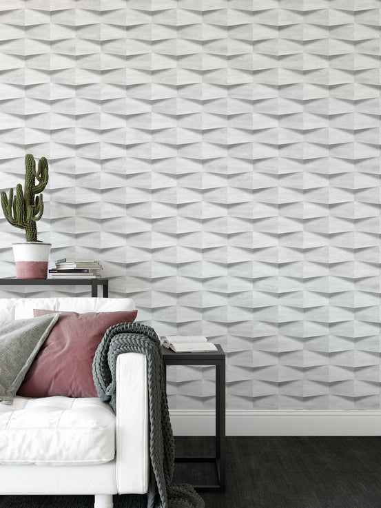 White 3D geometric wallpaper in a living room with a cactus and white sofa.