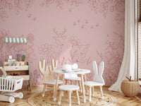 Nature themed pink wall mural in a nursery with a white rabbit-eared chair.