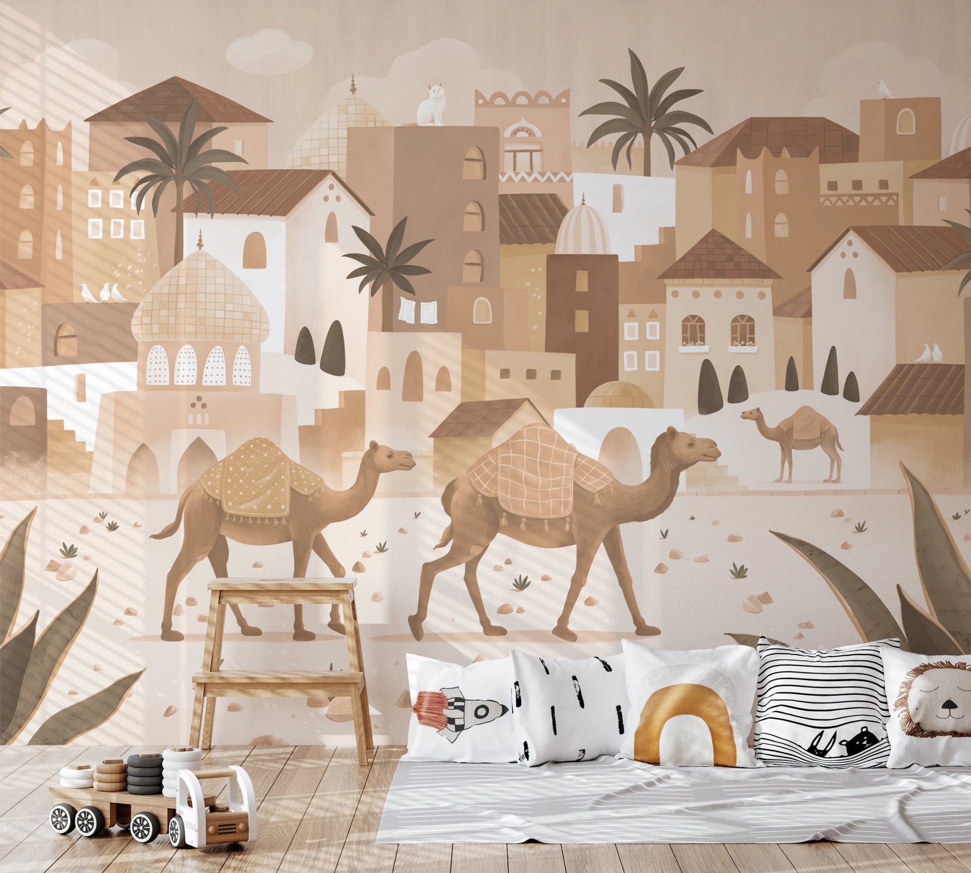 Nursery wall mural with a desert village scene behind a light wood crib.