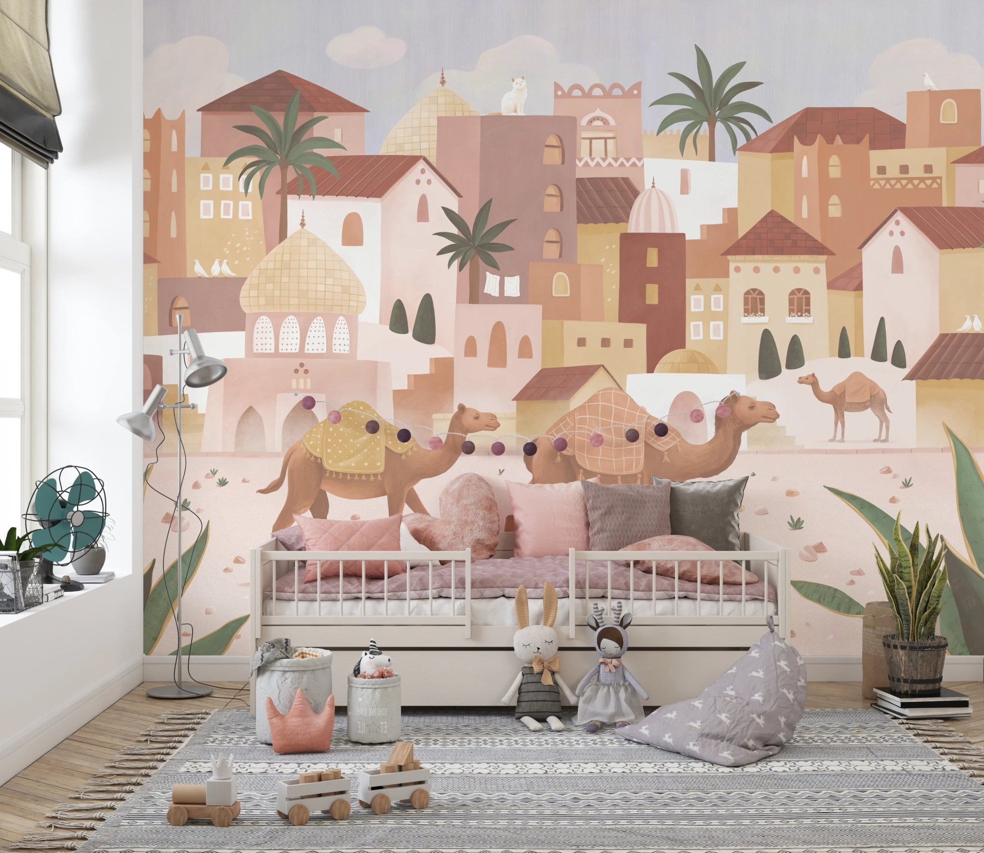 Desert Dreams Wall Mural behind a white toddler bed with grey pillows and toys.
