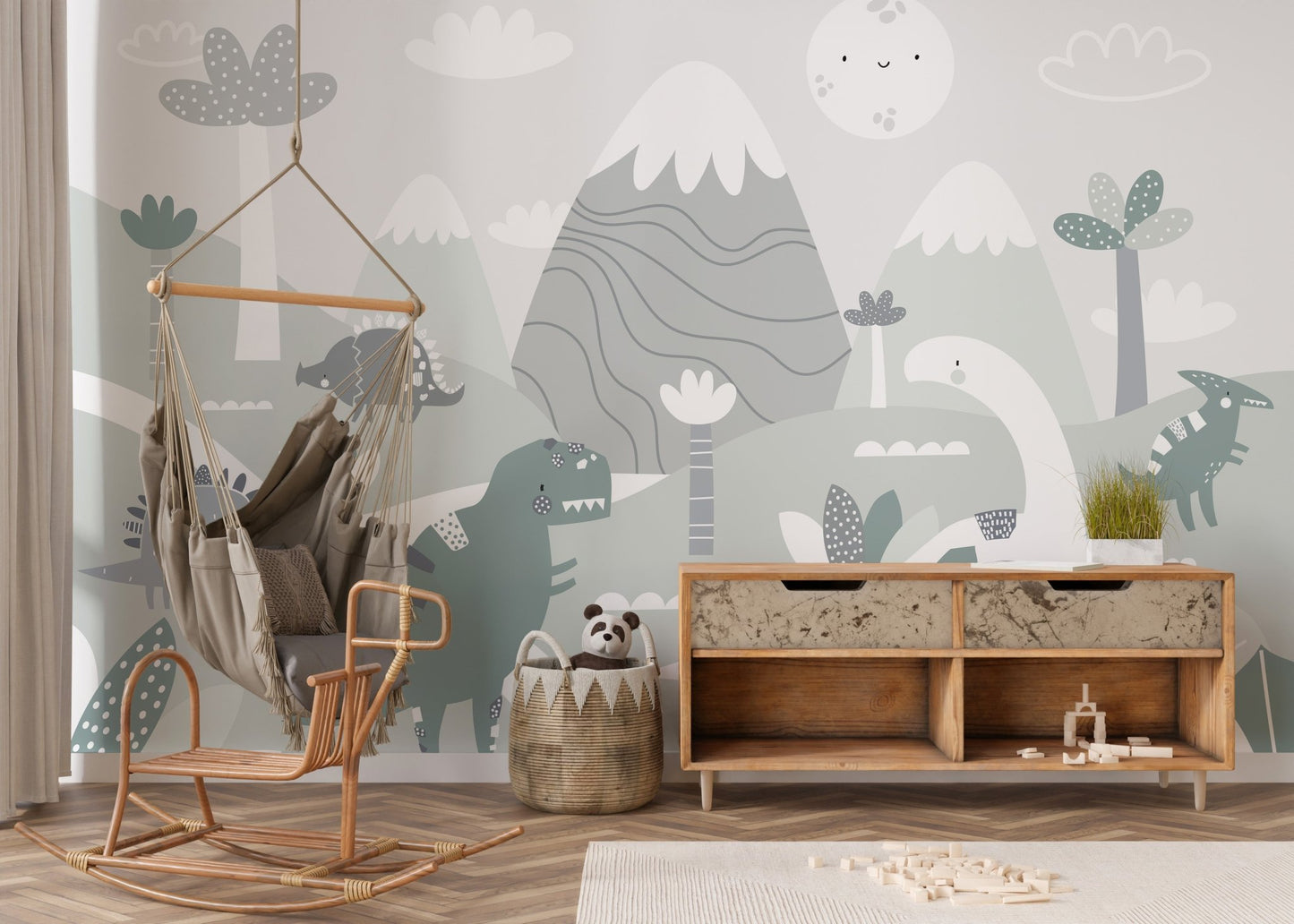 Neutral tone dinosaur wall mural behind a hanging chair and wooden sideboard in nursery.