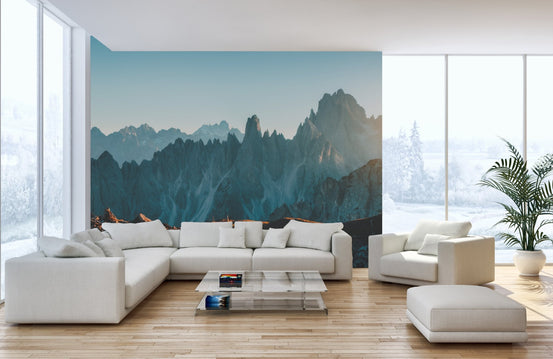 Modern white living room with dramatic rocky mountain wallpaper mural and sectional sofa.
