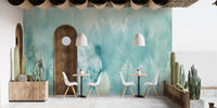 Cafe dining area with wooden furniture and a teal landscape wall mural background.