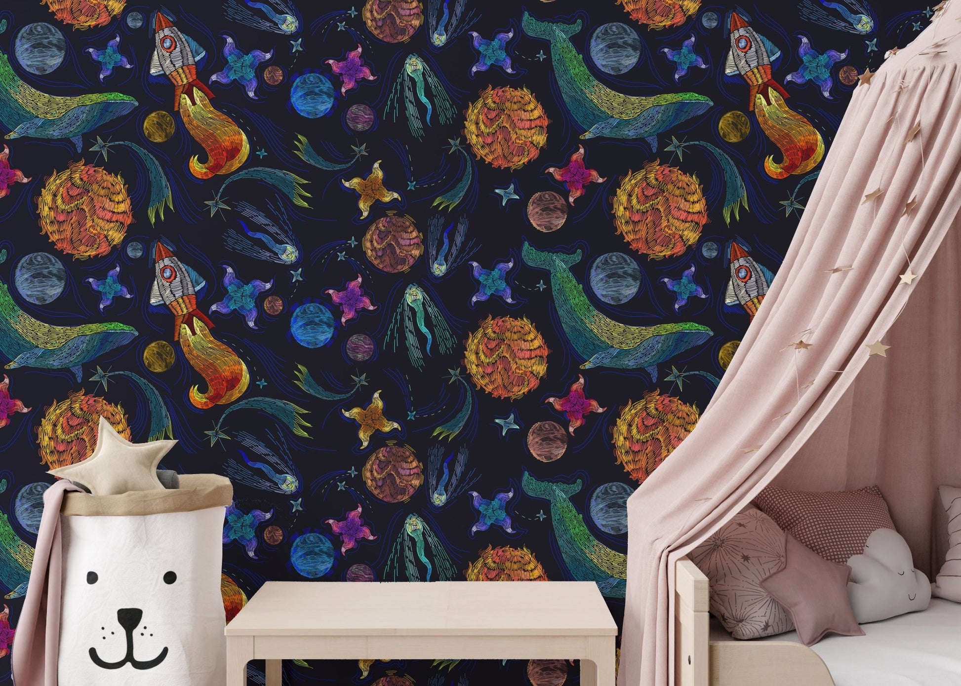 Embroidery style space wallpaper in a nursery with a pink canopy and white cot.