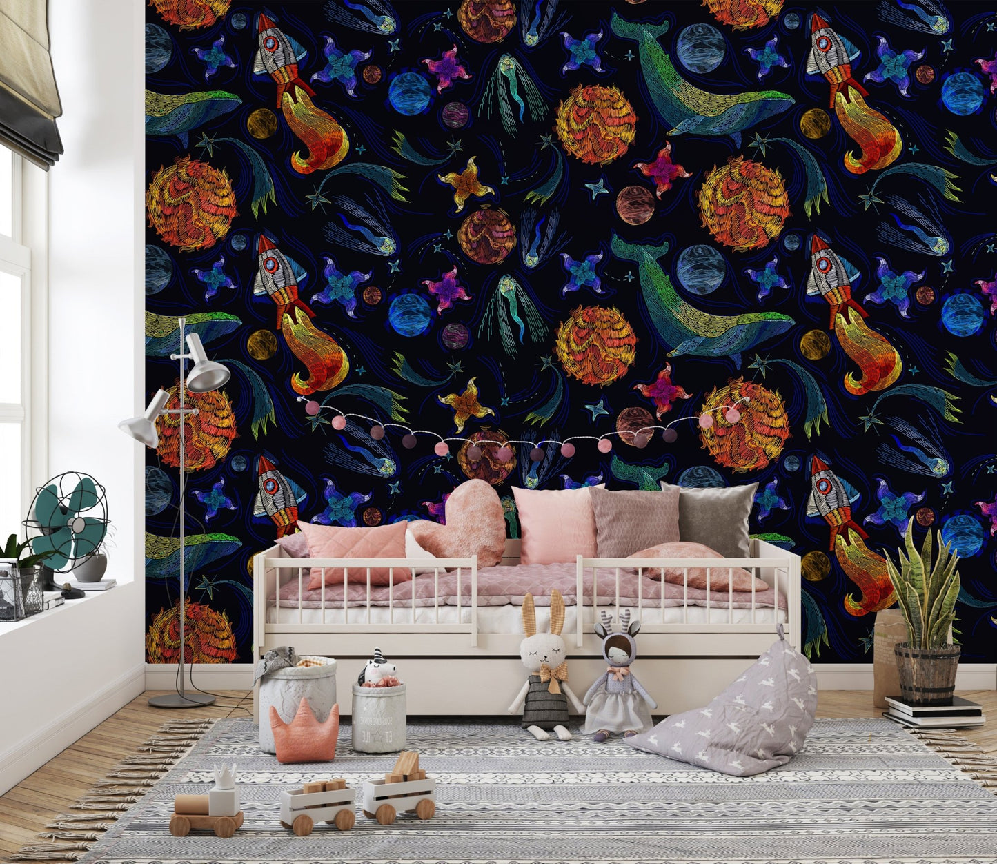Space adventure wallpaper in a kids' bedroom with a white daybed and pink pillows.