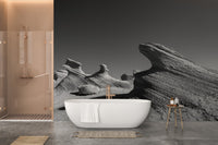 Grayscale desert rock wall mural in a bathroom with a white bathtub