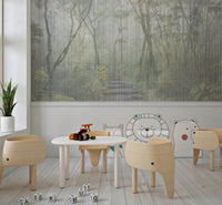 Kids play area with a forest wall mural behind small white tables and chairs.