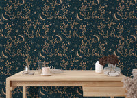 Minimalist desk with stationary and dark teal floral moon wallpaper backdrop.
