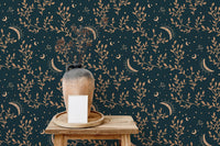 Wooden stool with a ceramic vase against esoteric crescent moon and floral wallpaper.