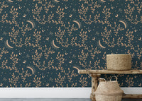 Low wooden bench with woven baskets in front of crescent moon and floral wallpaper.