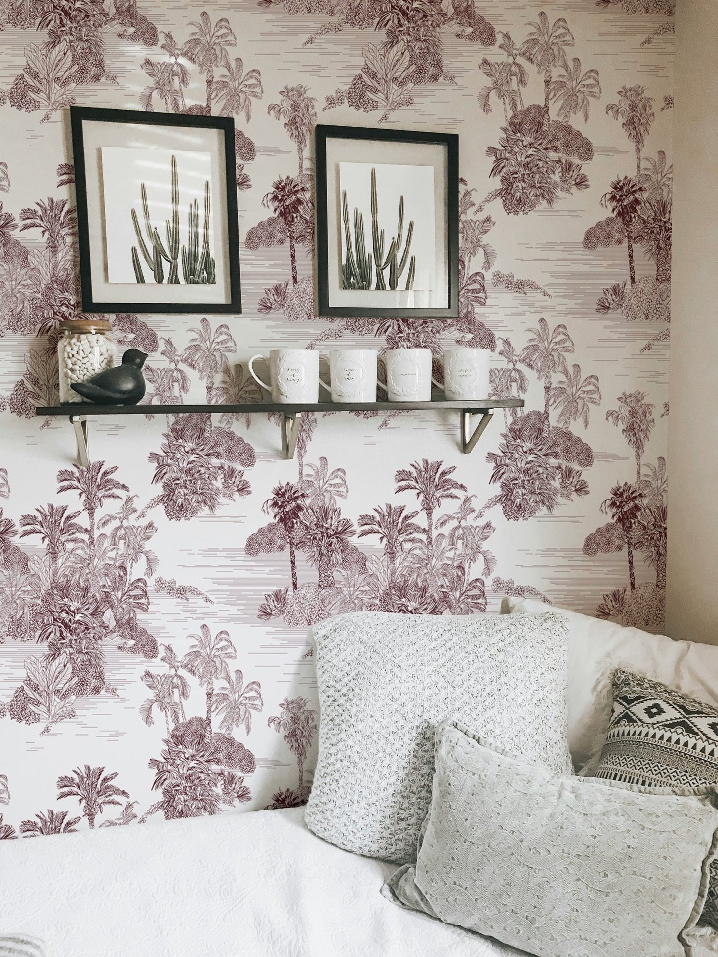 Brown tropical toile wallpaper decorated with wall frames and a floating shelf.