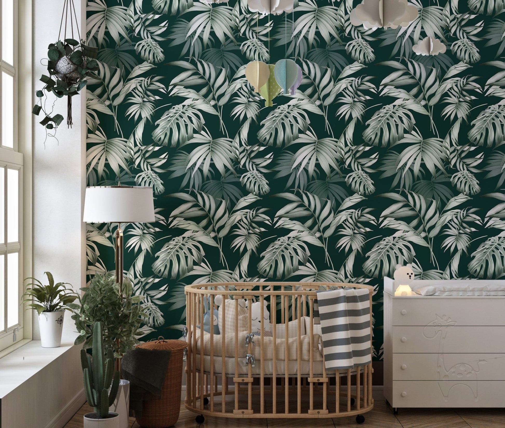 Palm leaf wallpaper in a nursery with a wooden crib and white dresser.