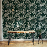 Exotic Jungle Tropical Green Leaves Repeat Wallpaper behind a minimalist wooden console.