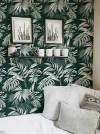 Dark green jungle wallpaper in a seating area with white cushions and frames.