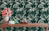 Exotic jungle wallpaper behind a wooden table with pink flowers in a vase.