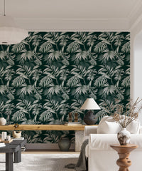 Dark green leaf wallpaper in a living space with a white sofa and desk.