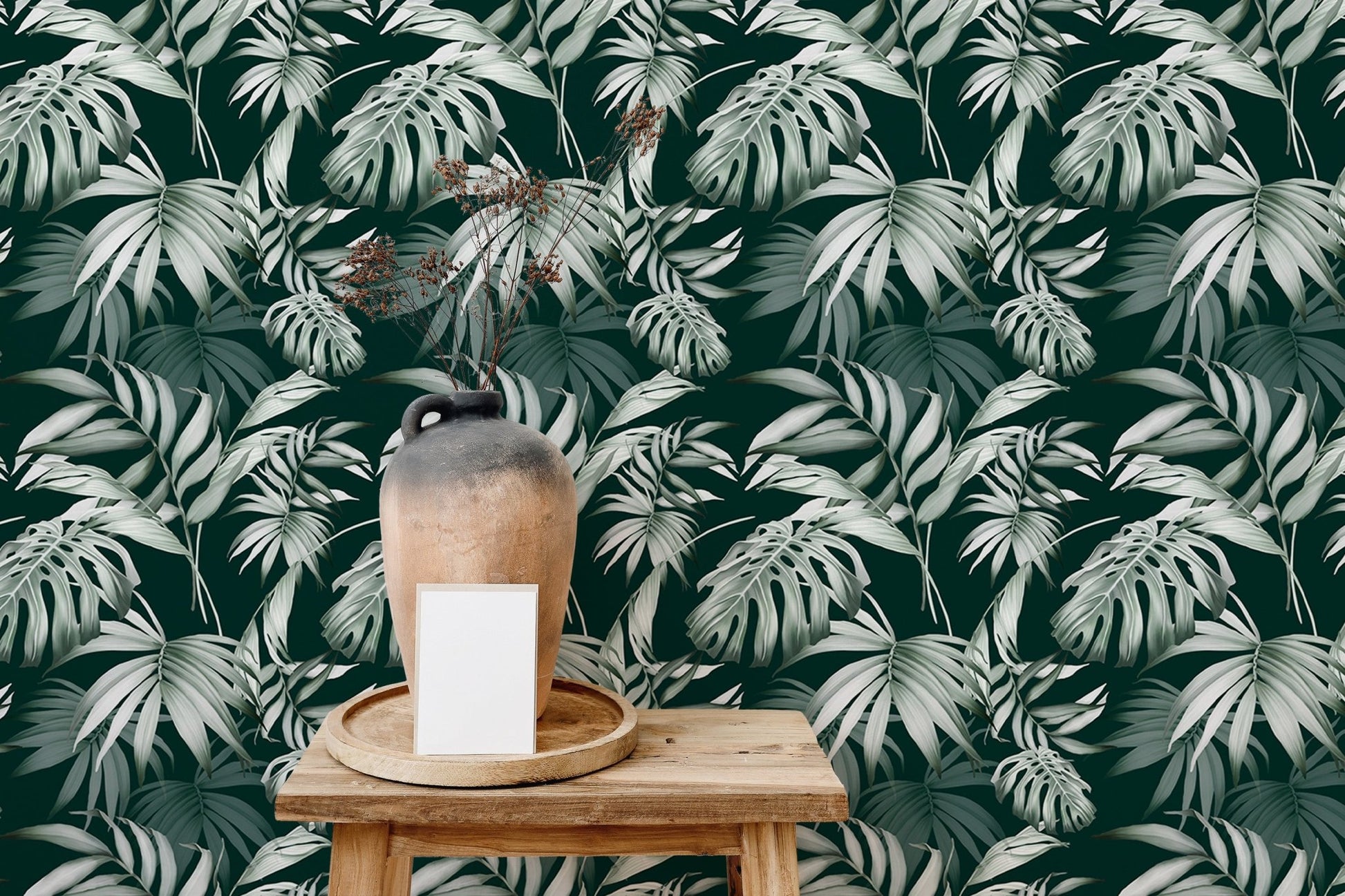 Tropical repeat wallpaper behind a wooden stool and a ceramic vase.