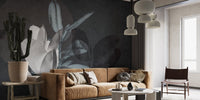 Tan sofa in a living area with dark leaf texture wall mural.