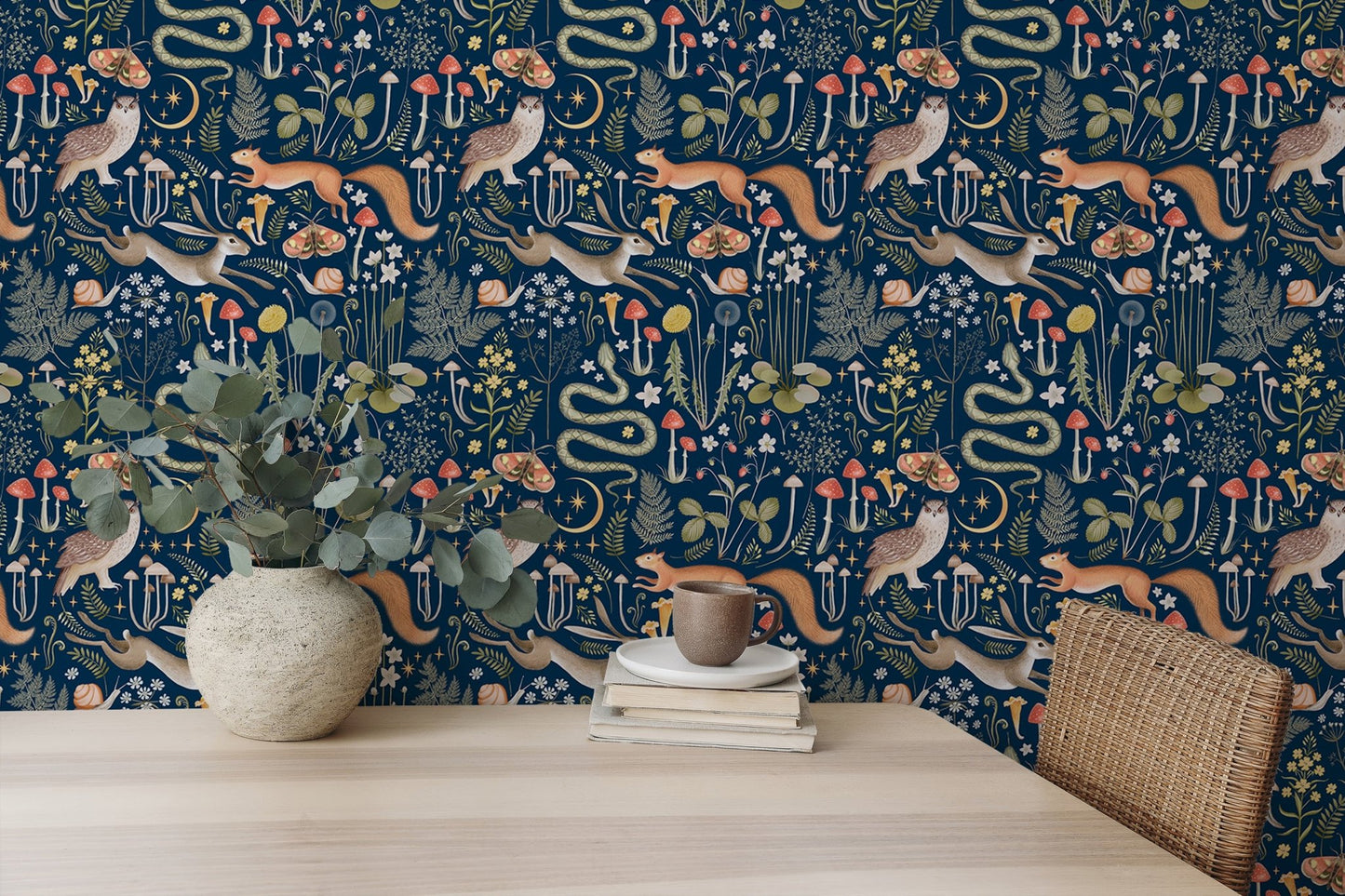 Dark blue fairy forest wallpaper behind a wooden desk with a white vase in dining area.