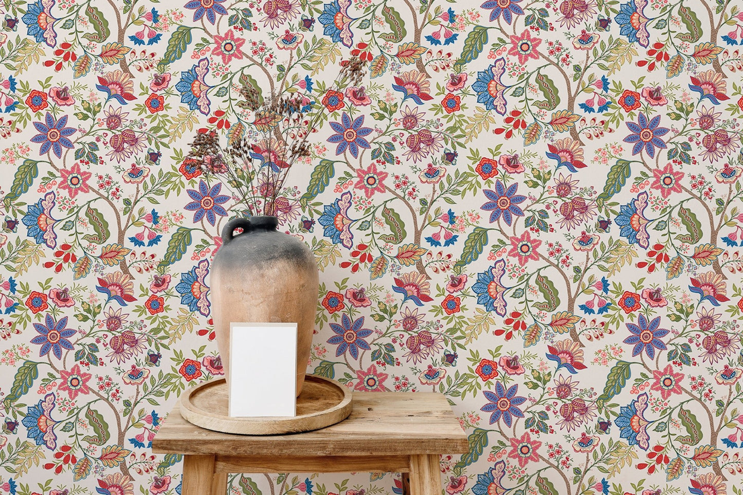 Decorative vase on a wooden stool with a floral jacobean pattern wallpaper.