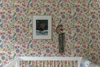 Nursery crib against fantasy flowers retro vintage jacobean embroidery style wallpaper.