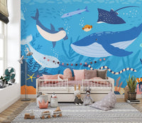 Blue ocean life wall mural behind a pink bed with a grey rug in nursery.