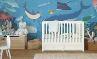 Marine life wall mural behind a white crib in a neutral nursery.