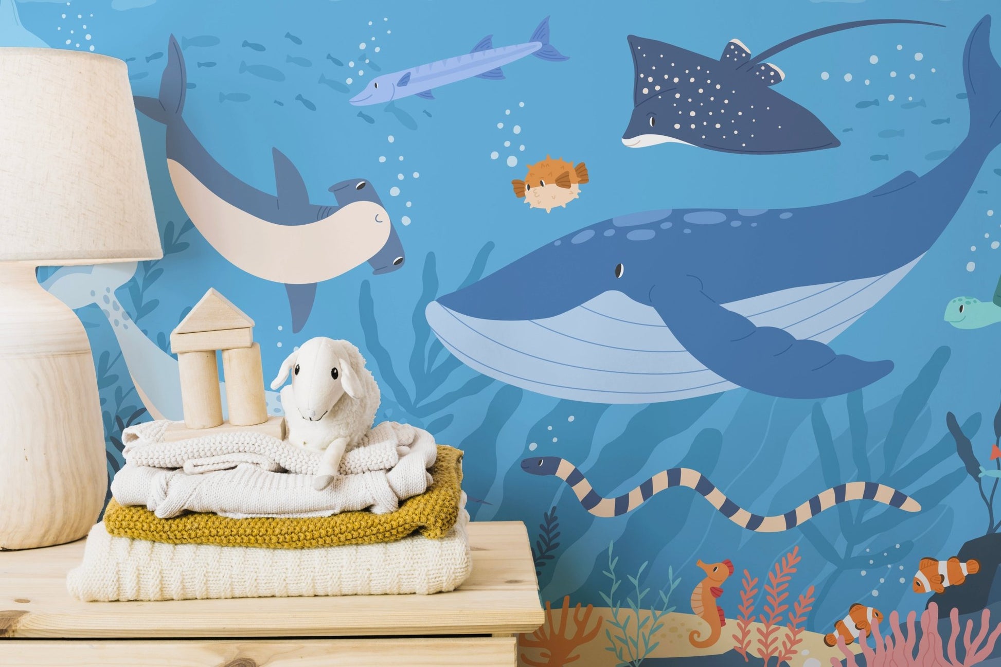 Underwater theme wall mural on a shelf with folded clothes and toys.