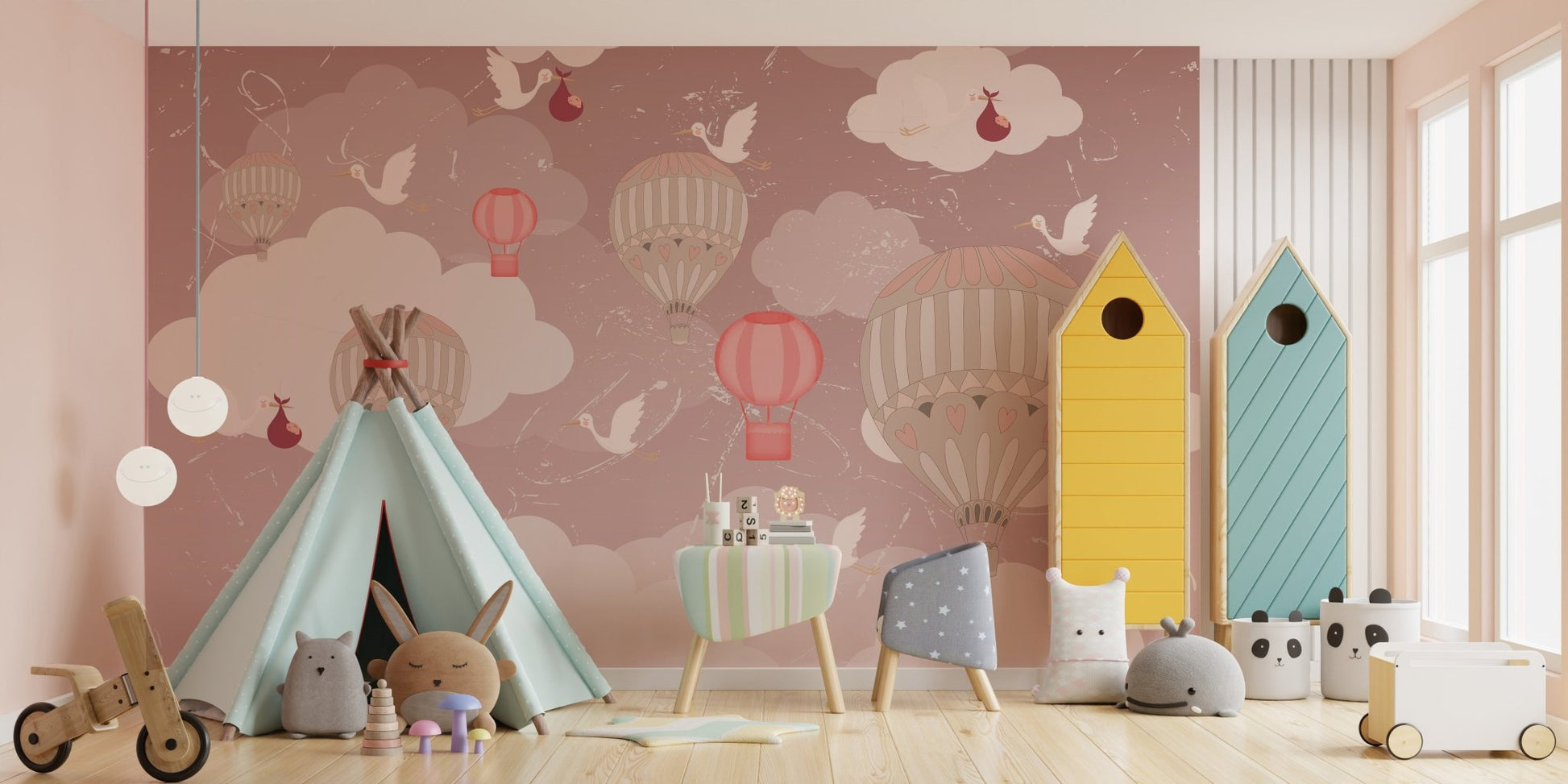 Nursery wall mural with stork and balloon illustrations behind colorful storage units.